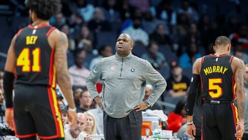 Hawks head coach Nate McMillan, center, stands on the court as forward Saddiq Bey (41) and guard Dejounte Murray (5) walk to the bench during a timeout during the second half of an NBA basketball game against the Charlotte Hornets in Charlotte, N.C., Monday, Feb. 13, 2023. (AP Photo/Nell Redmond)