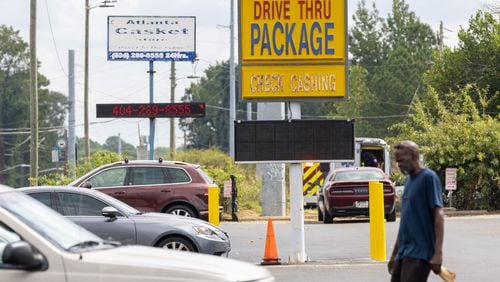 A person walks through the parking lot of a strip of businesses along Glenwood Road near its intersection with Columbia Drive in southern DeKalb County. on Wednesday, September 25, 2024. (Arvin Temkar / AJC)