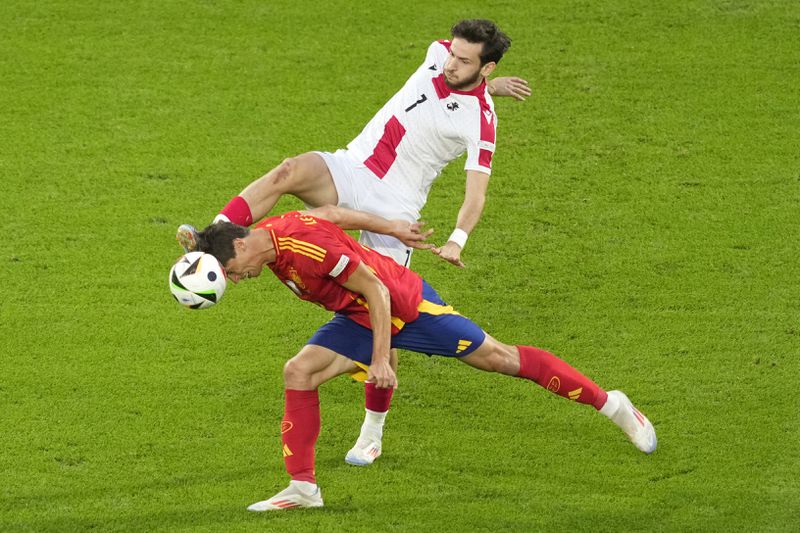Spain's Robin Le Normand challenges for the ball with Georgia's Khvicha Kvaratskhelia during a round of sixteen match between Spain and Georgia at the Euro 2024 soccer tournament in Cologne, Germany, Sunday, June 30, 2024. (AP Photo/Andreea Alexandru)