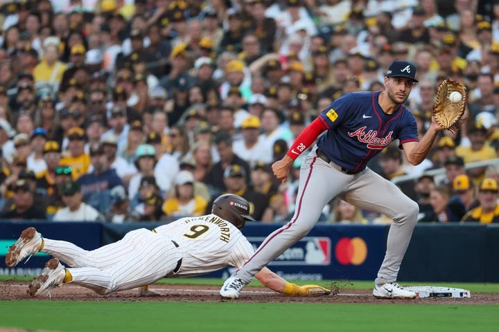 San Diego Padres’ Jake Cronenworth (9) dives back to first base while Atlanta Braves first base Matt Olson (28) covers during the second inning of National League Division Series Wild Card Game One at Petco Park in San Diego on Tuesday, Oct. 1, 2024.   (Jason Getz / Jason.Getz@ajc.com)