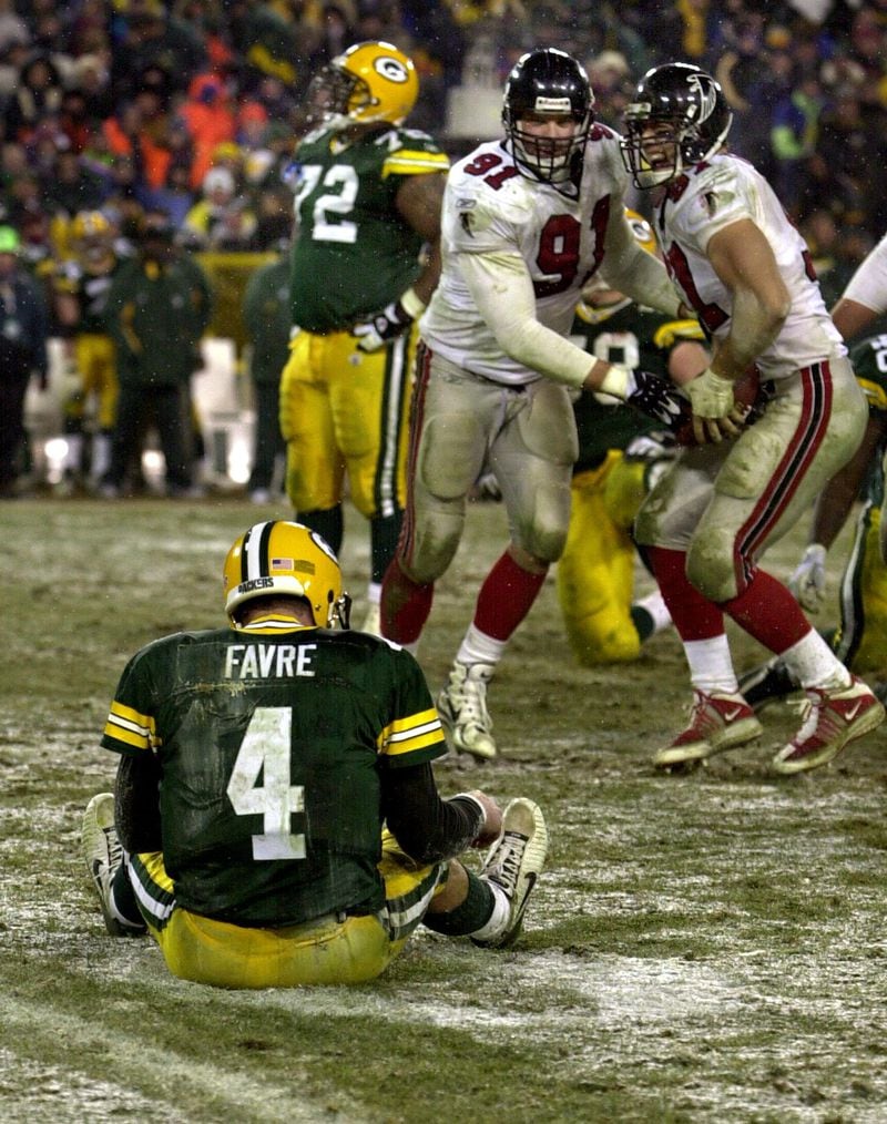Packers quarterback Brett Favre sits dejected in the snow as Falcons defensive ends Brady Smith (center) and Patrick Kerney come up with his fumble celebrating during 4th quarter. (Curtis Compton/AJC)