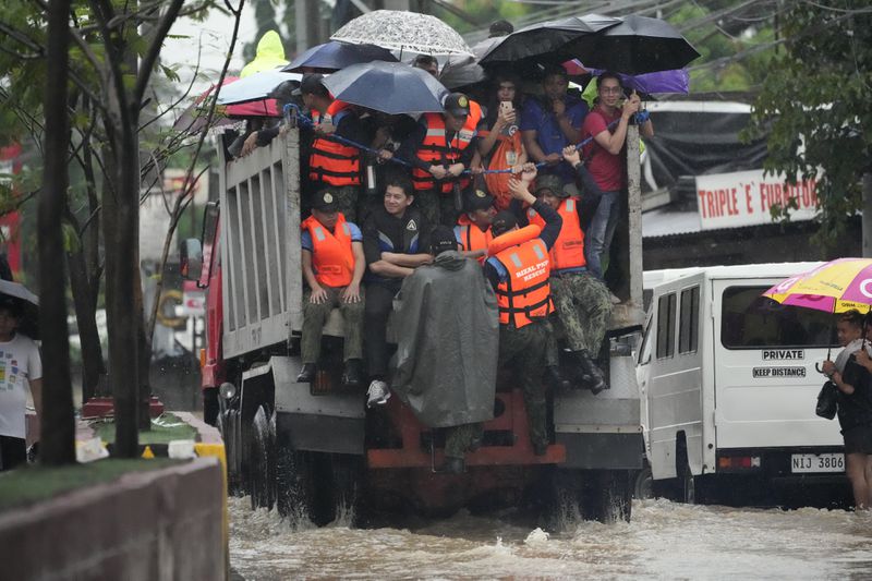 Rescuers and residents ride a truck as they cross a flooded street caused by heavy rains from Tropical Storm Yagi, locally called Enteng, in Cainta, Rizal province, Philippines, Monday, Sept. 2, 2024. (AP Photo/Aaron Favila)