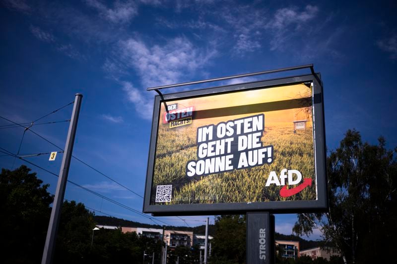 An electoral poster for the far-right Alternative for Germany, or AfD, using the slogan "The Sun Rises in the East", is displayed in a street in the federal state Thuringia city Jena, Germany, Wednesday, Aug. 14, 2024. In the federal state Thuringia, in former East Germany, the citizens are called to vote for a new state parliament on Sept. 1, 2024. (AP Photo/Markus Schreiber)