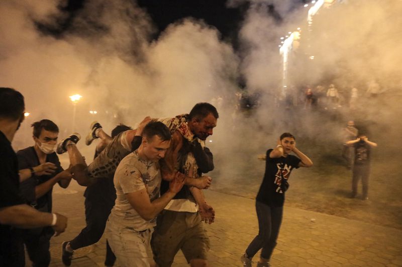 FILE - Protesters carry a man injured during clashes with police amid demonstrations in Minsk, Belarus, on Aug. 10, 2020. (AP Photo, File)