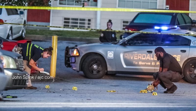  GBI agents take measurements between evidence markers in the parking lot of the Home Stay Suites in Riverdale on Monday morning. JOHN SPINK / JSPINK@AJC.COM