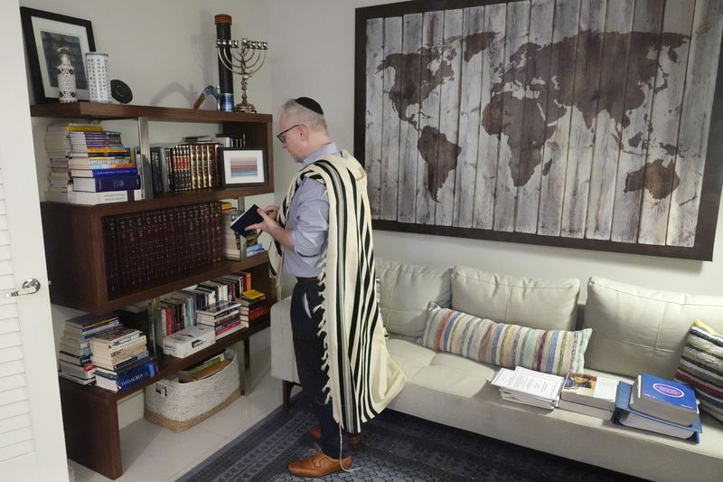 Daniel Gammerman gathers prayer items that he will use to privately worship at home during the Jewish High Holy Days, Thursday, Sept. 26, 2024, in Miami. (AP Photo/Wilfredo Lee)