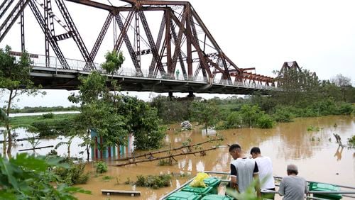 People watch the flooded Red river next to iconic Long Bien bridge, following Typhoon Yagi in Hanoi, Vietnam on Tuesday, Sept. 10, 2024. (AP Photo/Huy Han)