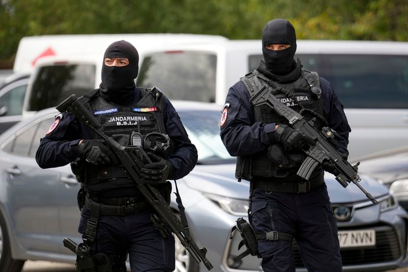 Armed gendarmes wearing balaclavas walk outside the residence of Andrew Tate during a police search raid, on the outskirts of Bucharest, Romania, Wednesday, Aug. 21, 2024. (AP Photo/Vadim Ghirda)