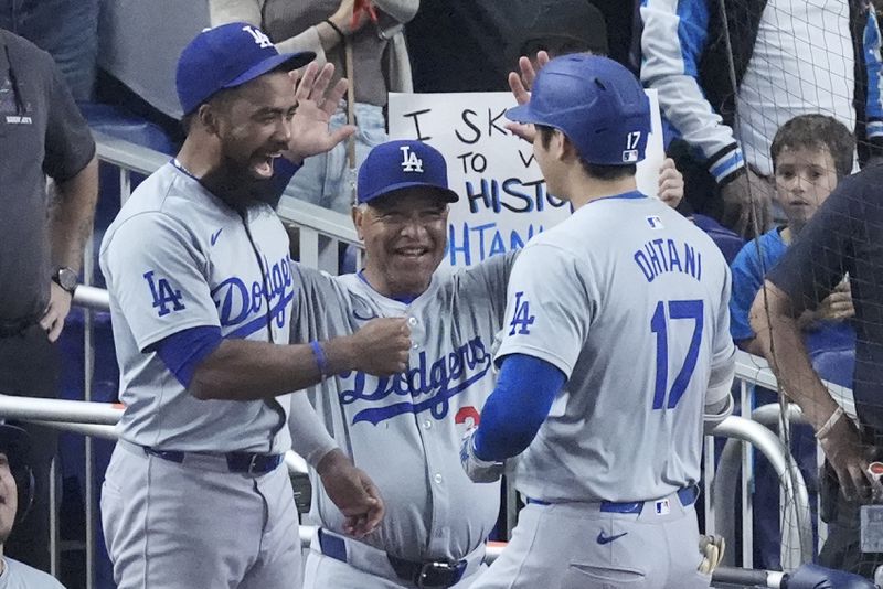 Los Angeles Dodgers' Teoscar Hernández, left, and manager Dave Roberts, center, congratulate Shohei Ohtani (17) after Ohtani hit a home run scoring Andy Pages during the sixth inning of a baseball game against the Miami Marlins, Thursday, Sept. 19, 2024, in Miami. (AP Photo/Wilfredo Lee)