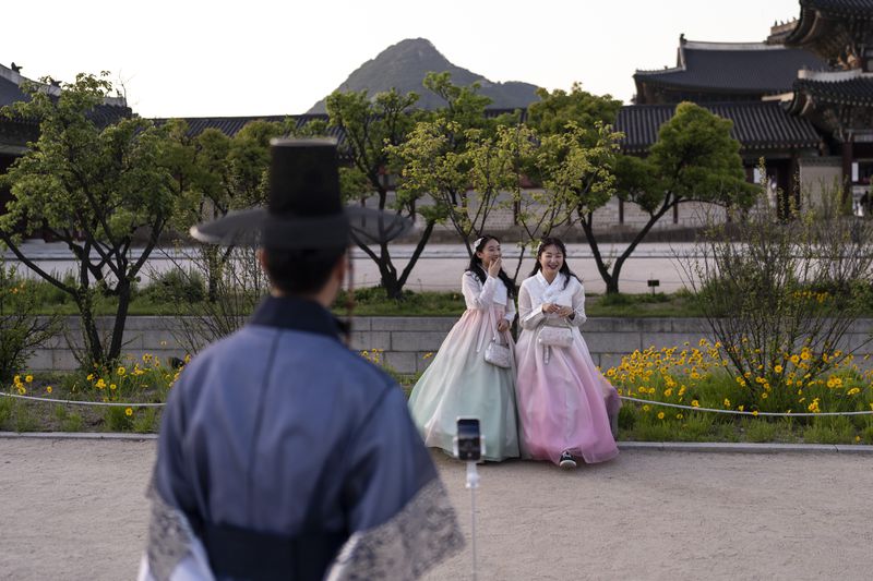 Two women dressed in traditional hanbok laugh as they pose for photos at Gyeongbok Palace, the main royal palace during the Joseon Dynasty, in Seoul, Thursday, May 23, 2024. (AP Photo/Jae C. Hong)d