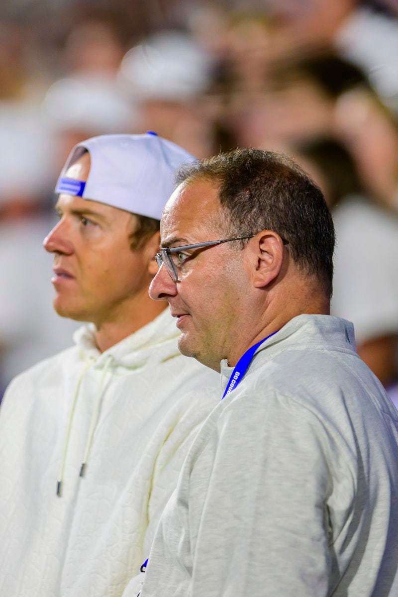 Ryan Smith, president and CEO of Smith Entertainment Group, left, hosts Adrian Wojnarowski, general manager of St. Bonaventure men's basketball, team during an NCAA college football game between BYU and Kansas State, Saturday, Sept. 21, 2024, in Provo, Utah. (AP Photo/Tyler Tate)