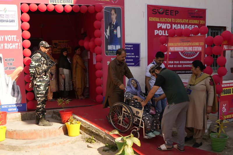 People help an elderly woman in a wheel chair down a ramp after she cast her vote during the first phase of the Jammu and Kashmir Assembly election, in Kishtwar, India, Wednesday, Sept. 18, 2024.(AP Photo/Channi Anand)