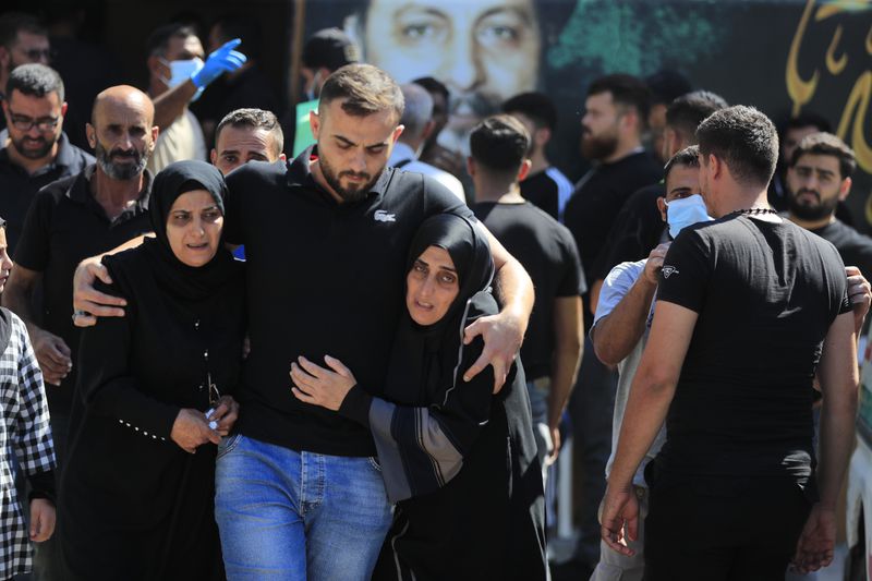 People react during the funeral procession of their relatives, who were killed in Monday's Israeli airstrikes, in the southern village of Saksakieh, Lebanon, Tuesday, Sept. 24, 2024. (AP Photo/Mohammed Zaatari)