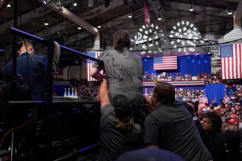 Police remove a man, center, who had climbed onto the media riser as Republican presidential nominee former President Donald Trump speaks at a campaign event, Friday, Aug. 30, 2024, in Johnstown, Pa. (AP Photo/Alex Brandon)