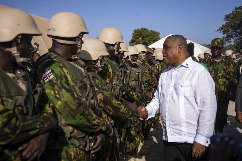 Haitian Prime Minister Garry Conille shakes hands with Kenyan police at their base in Port-au-Prince, Haiti, Wednesday, June 26, 2024. The first contingent of U.N.-backed foreign police arrived the previous day, nearly two years after the Caribbean country requested help to quell gang violence. (AP Photo/Marckinson Pierre)