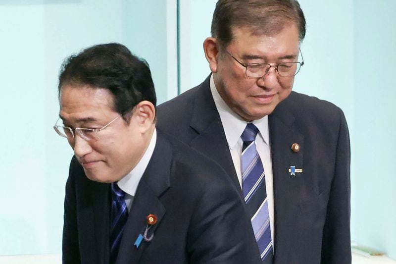 Japan's Prime Minister Fumio Kishida, left, walks past the newly elected head of the Liberal Democratic Party Shigeru Ishiba after the party's leadership election at its headquarters in Tokyo. on Sept. 27, 2024. (Japan Pool/Kyodo News via AP)