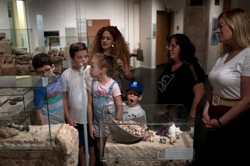 Ariel Heller, 4, center, yawns during the end of a special tour after the child accidentally broke an ancient jar at the Reuben and Edith Hecht Museum in Haifa, Israel, Friday, Aug. 30, 2024. The boy who accidentally broke a rare 3,500-year-old jar in an Israeli museum has been forgiven and invited back, as curators hope to turn the disaster into a teachable moment. (AP Photo/Maya Alleruzzo)