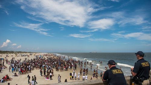 Police officers watch a crowd of partiers gather on the beach for Orange Crush Saturday afternoon at Tybee Island. The controversial pop up party was more restricted this year after an alcohol ban was set in place in addition to other laws being enforced. (Photo Courtesy of Josh Galemore/Savannah Morning News)