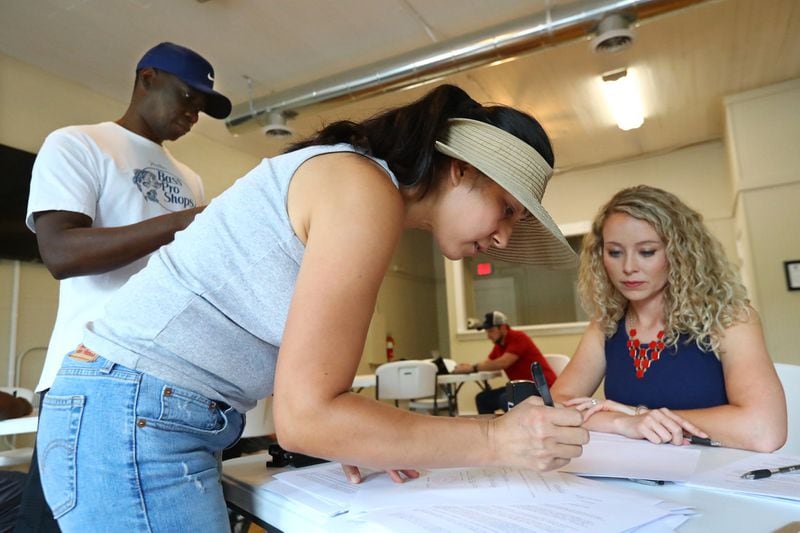 Residents Erica and Anthony Osula fill out complaints about the Hoschton mayor and a councilman as Jackson County Republican Chair Katie Griffin looks on. The county’s Democratic and Republican parties joined forces to help residents who want to force the mayor and a council member from office. CURTIS COMPTON/ccompton@ajc.com