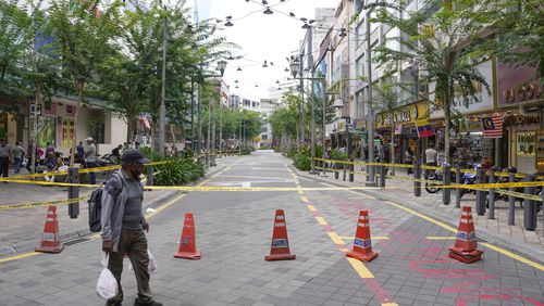 A man crosses a closed roadside after another deep sinkhole appeared a week after a woman fell into a sinkhole when a sidewalk caved in in Kuala Lumpur, Thursday, Aug. 29, 2024. (AP Photo/Vincent Thian)