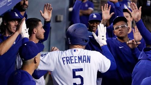 Freddie Freeman is congratulated by teammates in the dugout after hitting a solo home run during the first inning of a baseball game against the Atlanta Braves Monday, April 18, 2022, in Los Angeles. (AP Photo/Mark J. Terrill)