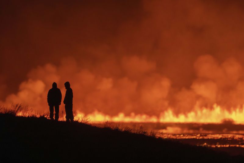 Tourists and visitors try to get a view of the eruption from a distance from the intersection between Reykjanesbraut, Iceland, and the road to Grindavik, Thursday, Aug. 22, 2024. (AP Photo/Marco di Marco)