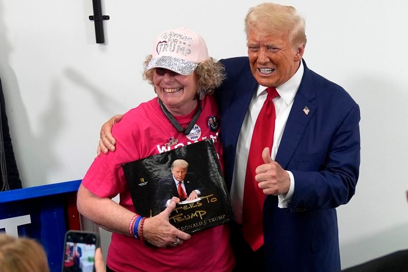 Republican presidential nominee former President Donald Trump, right, poses with a supporter during a stop at a campaign office, Monday, Aug. 26, 2024, in Roseville, Mich. (AP Photo/Carolyn Kaster)