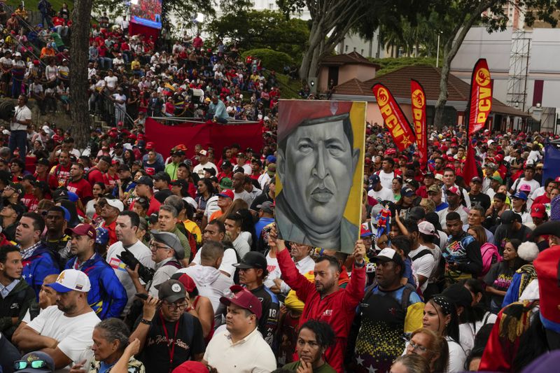 Government loyalists hold a poster of the late former President Hugo Chavez outside the presidential palace during a rally in support of President Nicolas Maduro's reelection one month after the presidential vote, in Caracas, Venezuela, Wednesday, Aug. 28, 2024. (AP Photo/Ariana Cubillos)