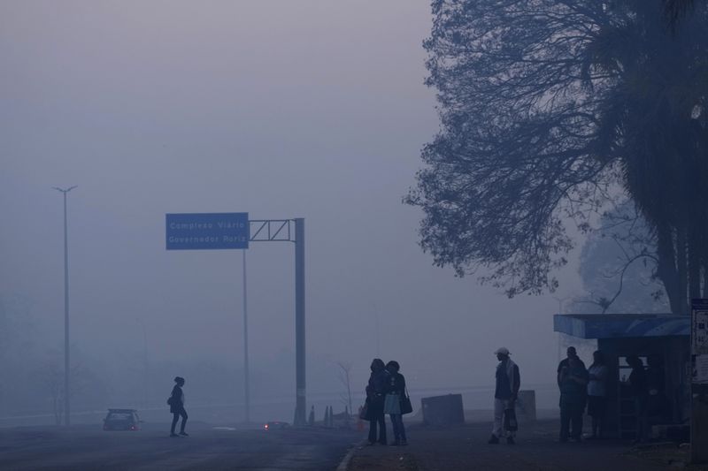 Smoke from a fire in the environmentally protected area of Brasilia National Park affects Brasilia, Brazil, early Monday, Sept. 16, 2024. The head of the agency that manages protected areas, Mauro Pires, told the local press that the fire is man-made and appears to have started near the edge of a farm. (AP Photo/Eraldo Peres)