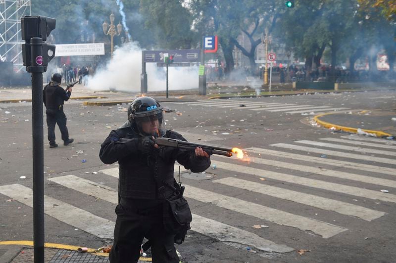 A police officer fires a weapon during clashes with anti-government protesters outside Congress, where lawmakers debate a reform bill promoted by President Javier Milei in Buenos Aires, Argentina, Wednesday, June 12, 2024. (AP Photo/Gustavo Garello)