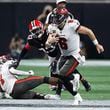 Tampa Bay Buccaneers quarterback Baker Mayfield (6) runs way from Atlanta Falcons cornerback Antonio Hamilton Sr. (33) during the second half of an NFL football game Thursday, Oct. 3, 2024, in Atlanta. (AP Photo/Butch Dill)