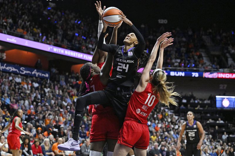 Connecticut Sun forward DeWanna Bonner (24) pulls up for a basket between the defense of Indiana Fever forward Aliyah Boston (7) and guard Lexie Hull (10) during the second half in Game 2 of a first-round WNBA basketball playoff series, Wednesday, Sept. 25, 2024, in Uncasville, Conn. (AP Photo/Jessica Hill)