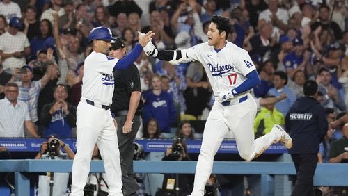 Los Angeles Dodgers designated hitter Shohei Ohtani (17) greets third base coach Dino Ebel as he runs the bases after hitting a grand slam during the ninth inning of a baseball game against the Tampa Bay Rays in Los Angeles, Friday, Aug. 23, 2024. The Dodgers won 7-3. Will Smith, Tommy Edman, and Max Muncy also scored. (AP Photo/Ashley Landis)