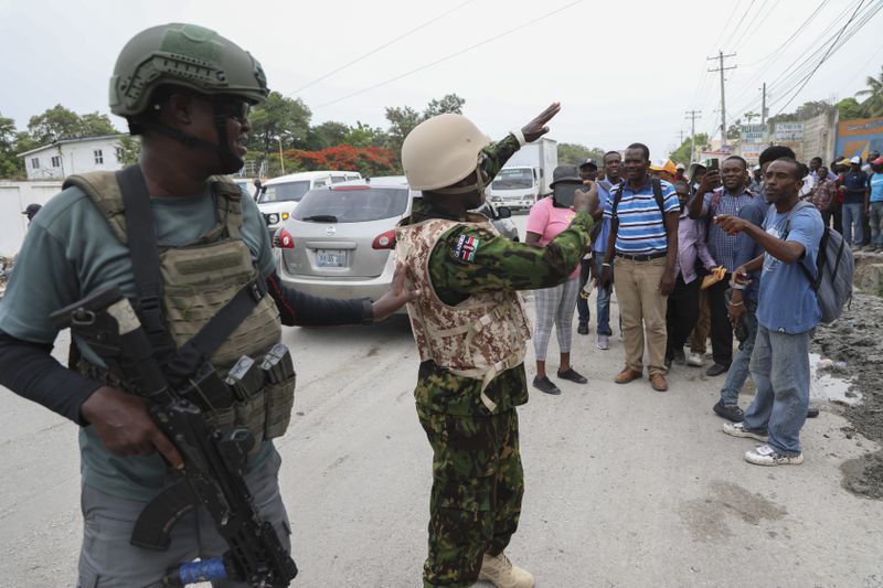A Kenyan police officer takes candid photos of a group of Haitians welcoming the officers, in Port-au-Prince, Haiti, Wednesday, July 3, 2024. (AP Photo/Odelyn Joseph)