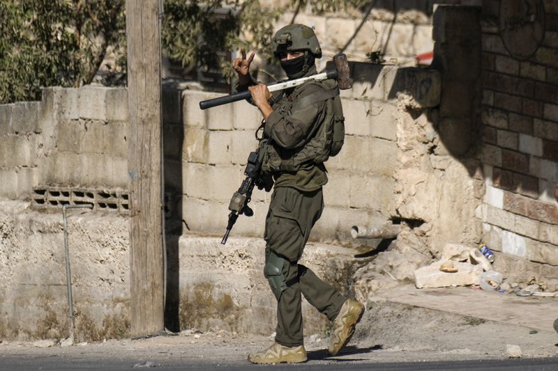 An Israeli soldier flashes a V-sign to photographers during an army raid in Tubas, West Bank, on Wednesday, Sept. 11, 2024. (AP Photo/Majdi Mohammed)