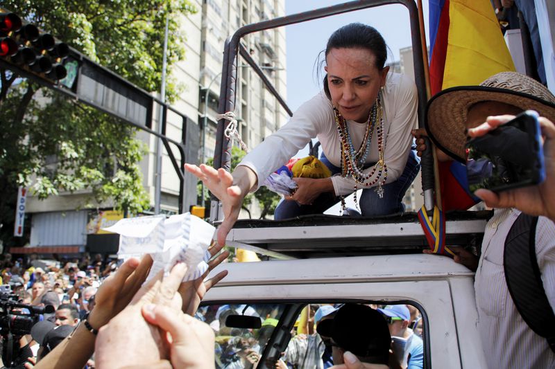 Opposition leader Maria Corina Machado reaches out to grab vote tally sheets during a rally to protest official results that declared President Nicolas Maduro the winner of the July presidential election, in Caracas, Venezuela, Saturday, Aug. 17, 2024. (AP Photo/Cristian Hernandez)