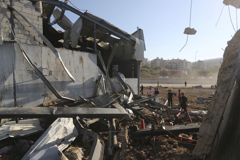 People gather at the site of an Israeli airstrike that hit a hangar in the southern town of Jiyeh, Lebanon, Wednesday, Sept. 25, 2024. (AP Photo/Mohammed Zaatari)