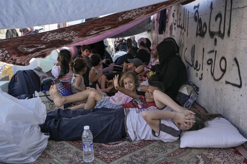 Children with their families lie on the ground in Beirut's Martyrs' square after fleeing the Israeli airstrikes in Beirut's southern suburbs, Saturday, Sept. 28, 2024. (AP Photo/Bilal Hussein)