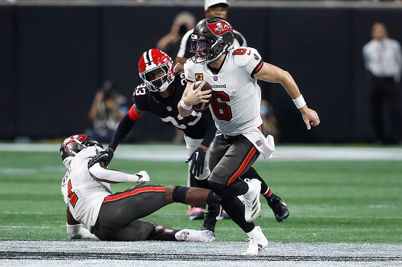 Tampa Bay Buccaneers quarterback Baker Mayfield (6) runs way from Atlanta Falcons cornerback Antonio Hamilton Sr. (33) during the second half of an NFL football game Thursday, Oct. 3, 2024, in Atlanta. (AP Photo/Butch Dill)