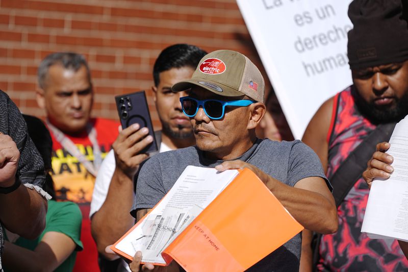 Resident Moises Didenot shows his receipts that he paid rent for his basement apartment during a rally staged by the East Colfax Community Collective to address chronic problems in the buildings occupied by people displaced from their home countries in central and South America Tuesday, Sept. 3, 2024, in Aurora, Colo. (AP Photo/David Zalubowski)