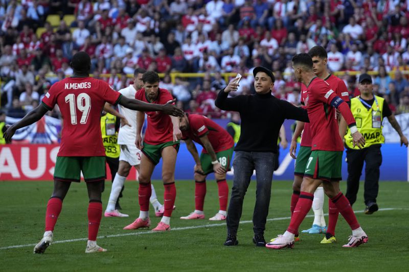 A pitch invader tries to take a selfie with Portugal's Cristiano Ronaldo during a Group F match between Turkey and Portugal at the Euro 2024 soccer tournament in Dortmund, Germany, Saturday, June 22, 2024. (AP Photo/Themba Hadebe)