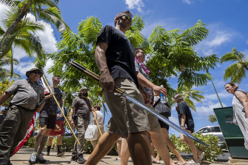 Members of Hawaii Firearms Coalition walk around Waikiki with their non-firearm weapons on Saturday, June 22, 2024, in Honolulu, Hawaii. (AP Photo/Mengshin Lin)