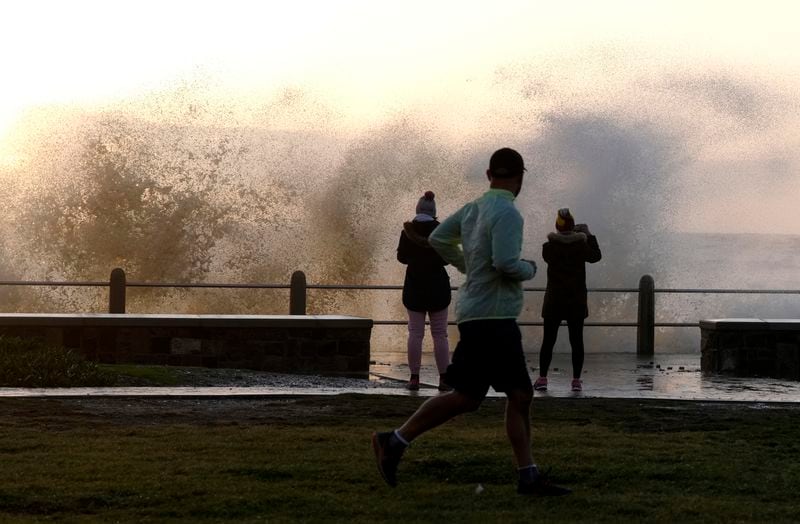 Waves break over Sea Point's promenade in Cape Town, South Africa, Monday, July 8, 2024. City authorities say nearly 1,000 homes in informal settlements around the city have been destroyed by gale-force winds, displacing around 4,000 people with multiple cold fronts expected until at least Friday. (AP Photo/Nardus Engelbrecht)