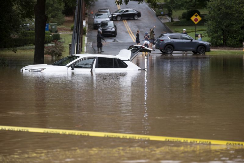 A partially submerged car sits on Sagamore Drive after Peachtree Creek spills over its banks in Atlanta on Friday, Sept. 27, 2024, following a night of heavy rain from Hurricane Helene. Ben Gray for the Atlanta Journal-Constitution