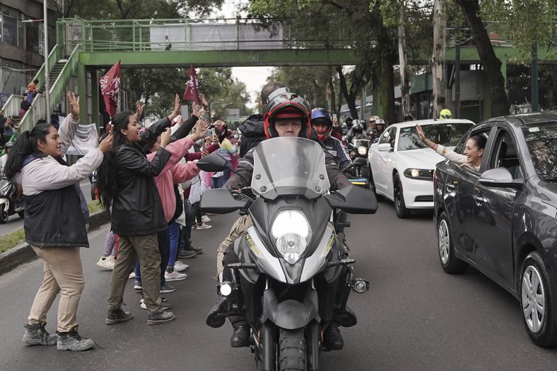 Claudia Sheinbaum waves to supporters from the vehicle taking her to Congress to assume the presidency in Mexico City, Tuesday, Oct. 1, 2024. (AP Photo/Aurea Del Rosario)