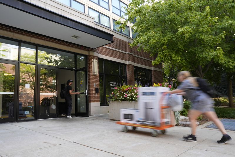 A student delivers packages to the dormitory at DePaul University in Chicago, Wednesday, Aug. 28, 2024. (AP Photo/Nam Y. Huh)