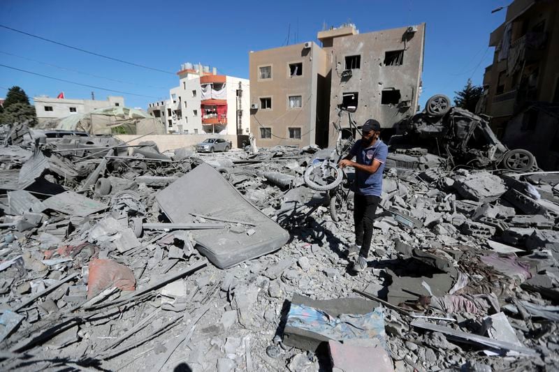 A man carries a damaged bicycle at the site of an Israeli airstrike in Saksakieh, south Lebanon, Thursday, Sept. 26, 2024. (AP Photo/Mohammed Zaatari)