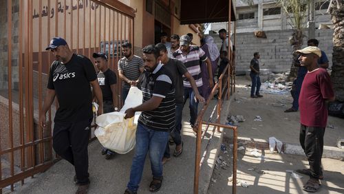 Mourners carry the covered bodies of Palestinians who were killed in an Israeli airstrike on a crowded tent camp housing Palestinians displaced by the war in the Muwasi, outside the hospital morgue in Deir al-Balah, Gaza Strip, Tuesday, Sept. 10, 2024. (AP Photo/Abdel Kareem Hana)