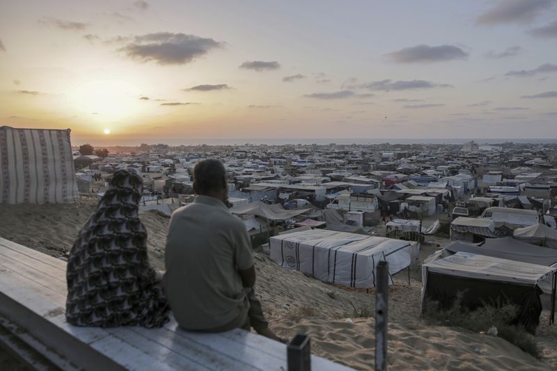 Palestinians displaced by the Israeli air and ground offensive on the Gaza Strip sit at a makeshift tent camp in Khan Younis, Gaza, Tuesday, June 18, 2024. (AP Photo/Jehad Alshrafi)