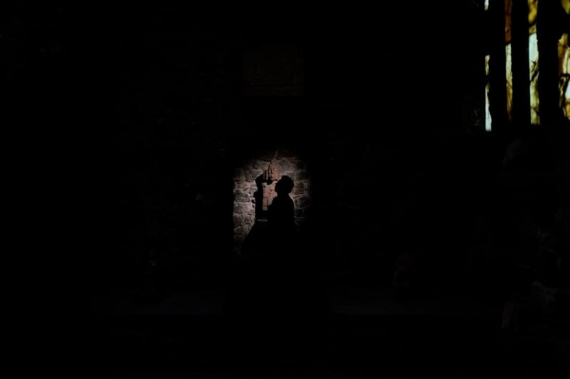 A visitor is silhouetted against an interior wall of the Anahuacalli Museum in Mexico City, Tuesday, Aug. 20, 2024. While its main floor represents the underworld — and feels dimly lit and cold — the second and third levels were inspired by the earthly and celestial worlds, which makes them seem warmer and flooded by light. (AP Photo/Eduardo Verdugo)